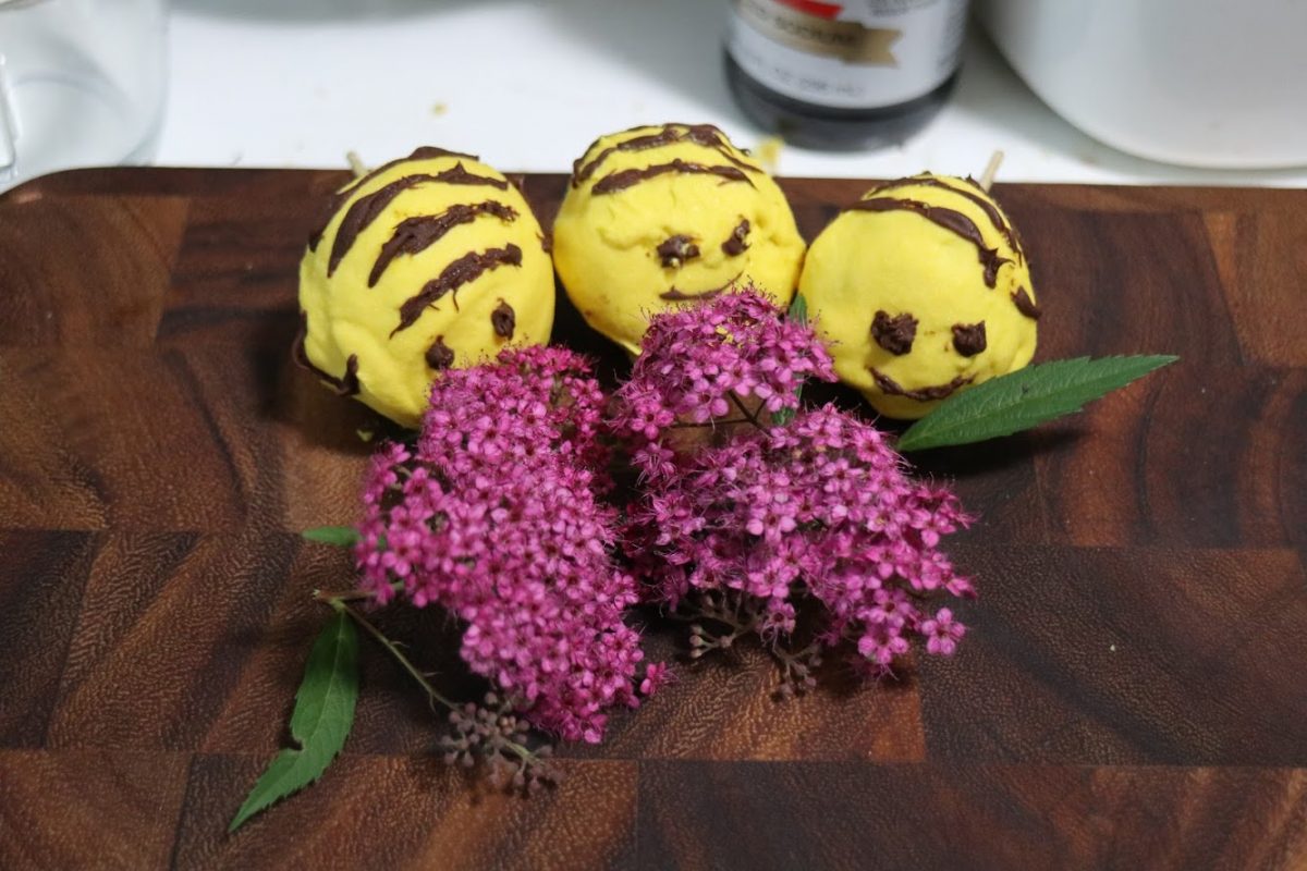 three bee pop cakes next to a flower
