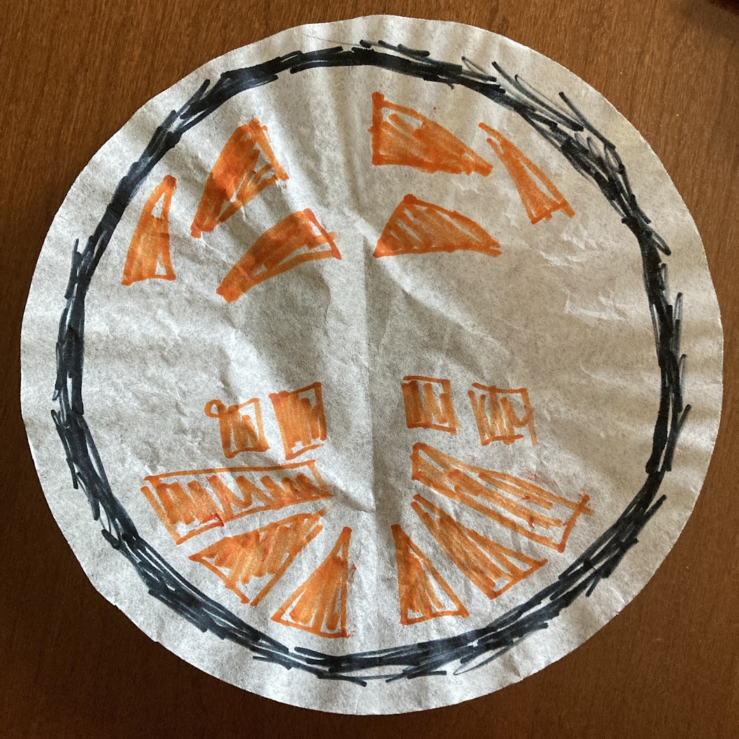 A coffee filter with an orange pattern of triangles and squares with a sketchy black circle drawn around the outside