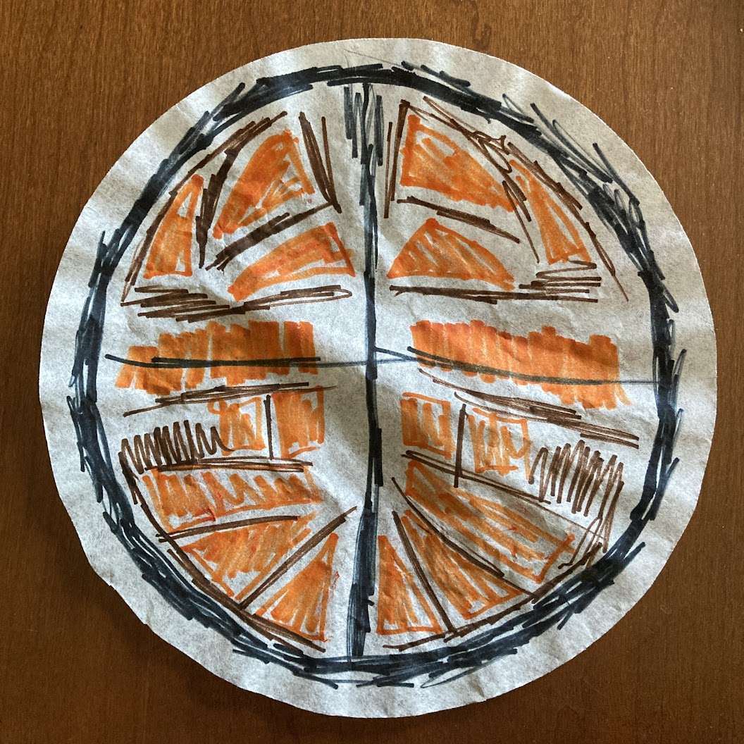 A coffee filter colored with marker showing a symmetrical orange and brown pattern surrounded a sketchy black circle around the outside and a black plus shape dividing it into quarters.