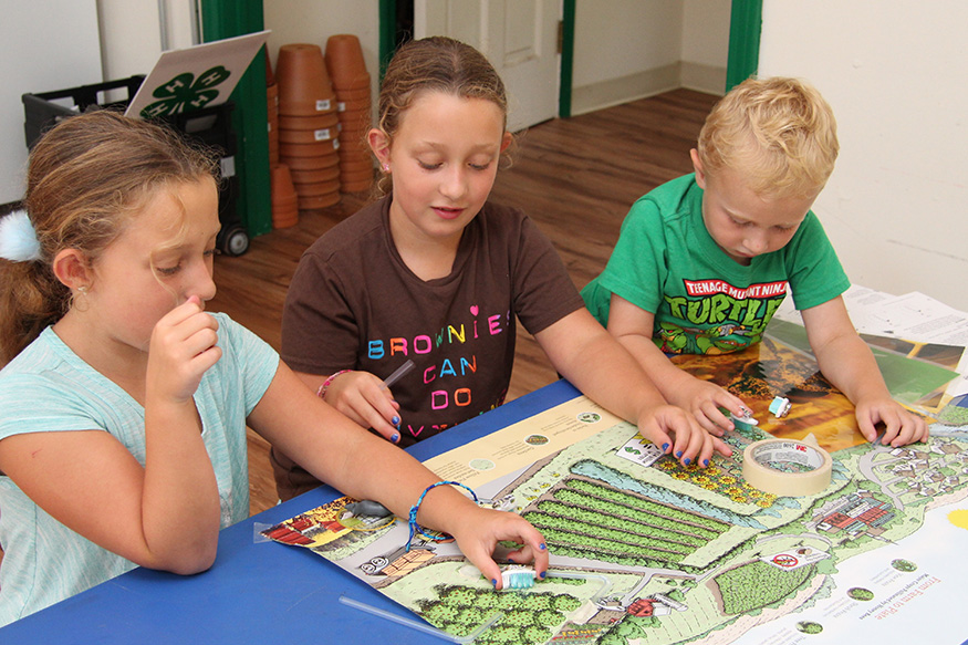 three kids sitting at a table playing a game