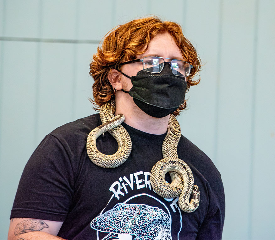 an Educator with a tan colored snake around his neck.